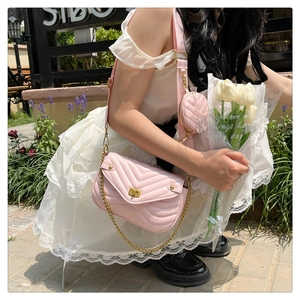 Close-up of pink quilted crossbody bag with gold chain and matching round mini pouch
