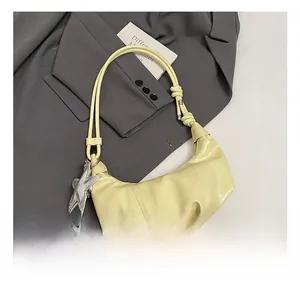 Detail of light yellow leather dumpling bag with knotted strap and star charm