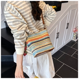 Close-up of color-block woven bucket bag featuring leather base and strawberry charm