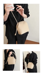 Detail view of the beige lychee pattern leather shell bag with gold zipper and strap