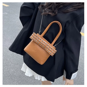 Close-up of brown pebbled leather bucket bag with silver rivets and metal chain strap