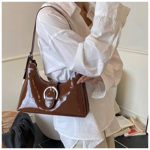 Detail of dark brown patent leather shoulder bag with a large silver horseshoe buckle