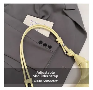 Detail of adjustable knotted shoulder strap on pale yellow crocodile pattern handbag