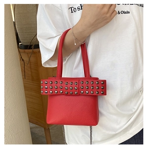 Détail du sac à main rouge en cuir PU avec clous argentés et bandoulière en chaîne