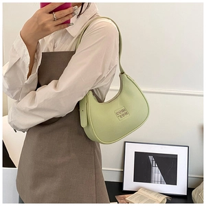 Detail of avocado green hobo bag featuring litchi texture and letter embossed logo