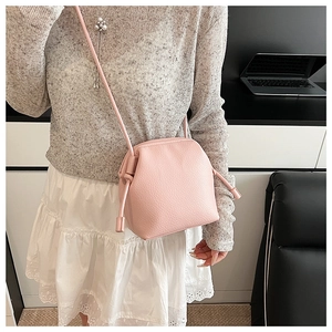 Detail view of pink lychee leather crossbody bag shown on model in modern setting