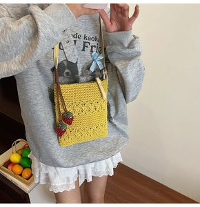Detail of yellow hollow knit bag with strawberry charms and cream shoulder strap