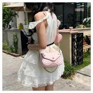 Detail of light pink quilted shoulder bag with chain strap and round coin purse