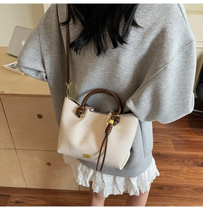 Dettaglio di una borsa tote intrecciata beige con manici marroni e logo dorato