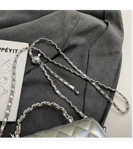 Detail of silver quilted chain bag with adjustable metal ball buckle and luxury texture