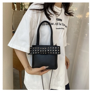 Détail du sac en cuir noir avec nœud à rivets argentés et bandoulière en chaîne