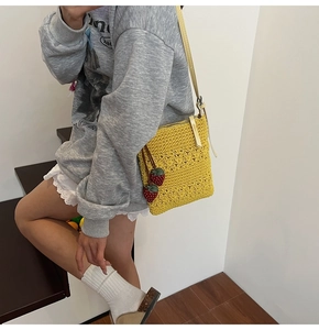 Detail of yellow crochet crossbody bag with 3D floral texture and strawberry charms