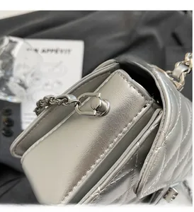 Macro view of silver quilted crossbody bag featuring polished metallic hardware detail