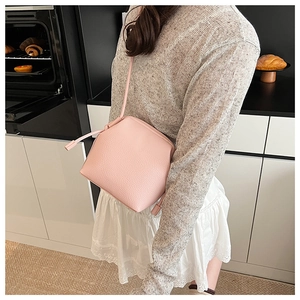 Sac seau rose en cuir grainé porté par un mannequin dans une cuisine au style moderne