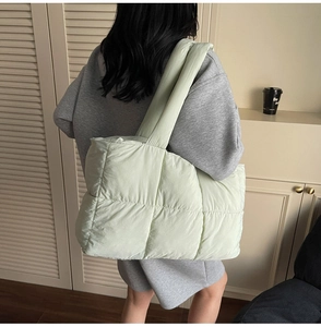Detail of mint green quilted tote bag showing soft puffy texture and wide shoulder strap