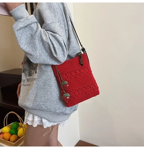 Macro detail of red crochet handbag with floral patterns and cute strawberry charms