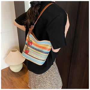 Detail of rainbow woven tote bag with strawberry charms and leather shoulder strap
