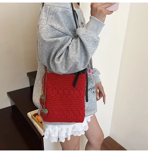 Detailed texture of red crochet shoulder bag featuring a cute strawberry charm accessory