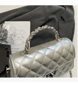 Detail of silver quilted flap bag featuring a metallic handle and silver twist lock clasp
