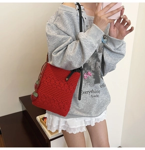 Detail of red crochet shoulder bag featuring a cute 3D strawberry charm and knit texture