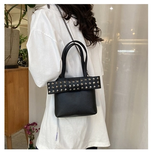 Close-up of black studded leather handbag with bow detail and silver chain strap