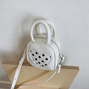 Close-up of white PU leather mini bucket bag with heart-shaped polka dot decoration