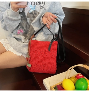 Close-up of red hand-woven shoulder bag featuring 3D floral textures and strawberry charms