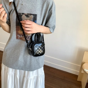 Close-up of black PU leather bucket bag with white polka dot heart on a female model