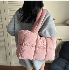 Detail of pink quilted down tote bag with wide strap on shoulder for women