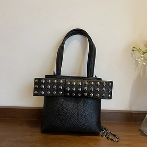 Black pebbled leather crossbody bag featuring a large studded bow and silver chain strap
