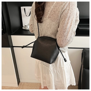 Detail of black lychee grain leather shell bag with unique drawstring side accents