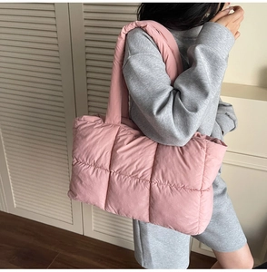 Pink quilted puffer tote bag with wide shoulder strap shown on model in modern room