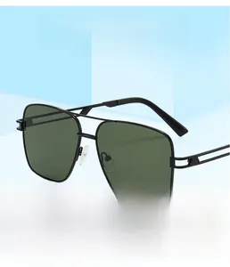 Detail of pilot-style sunglasses with black metal frame and dark green lenses on blue stand