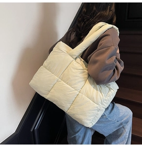 Detailed close-up of large quilted tote bag in light yellow on shoulder with wide strap