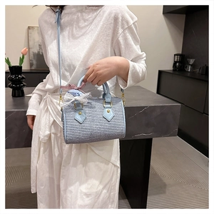 Gros plan sur un mini sac tonneau tissé bleu avec bordures dentelle et nœud vichy