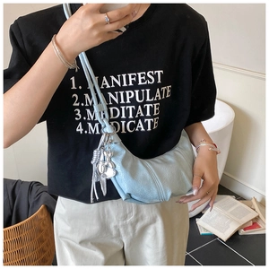 Détail du sac lune plissé bleu clair avec breloque lapin argenté sur tenue