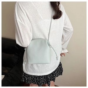 Detail view of light blue shell bag with lychee texture and decorative side knots