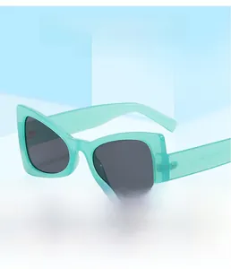 Close-up of mint green cat-eye sunglasses with dark grey lenses on a geometric stand