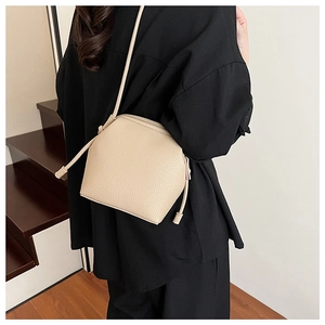 Detail view of cream-colored lychee textured bucket bag with knot shoulder strap detail