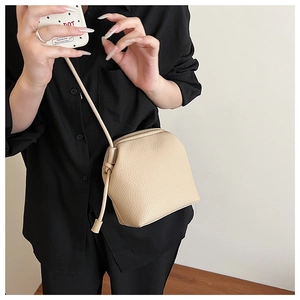 Close-up of beige grained leather bucket bag with decorative side drawstring knots