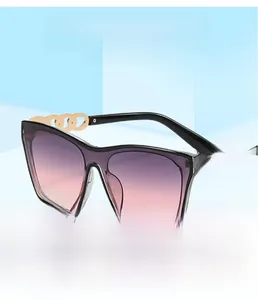 Detail of oversized square sunglasses featuring a golden metal chain-link temple design