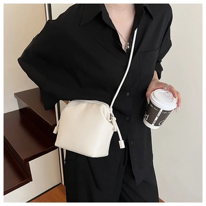 Detailed close-up of white lychee pattern leather crossbody cloud bag with metal zipper