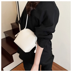 Vue latérale d'un sac à bandoulière en cuir grainé blanc avec un élégant détail de gland