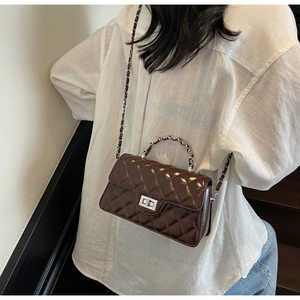 Detail of dark brown quilted chain crossbody bag styled with white shirt and jeans