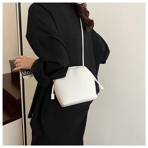 Detailed side view of white crossbody bag with decorative drawstrings on model
