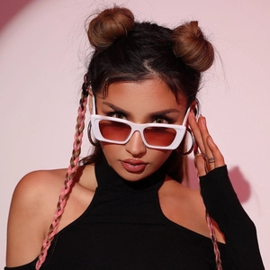 Close-up of white rectangular sunglasses with tinted lenses on a model with dreadlocks