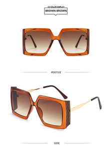 Detail of square amber sunglasses with brown gradient lenses and gold metal temples