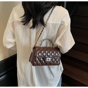 Detail of dark brown quilted crossbody bag with silver twist lock and chain strap