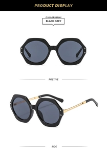 Detail view of black hexagonal sunglasses with grey lenses and gold metal temples