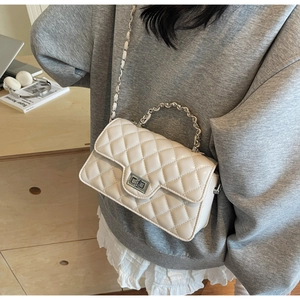 Close-up of quilted rhombus pattern on a beige shoulder bag with silver metal chain